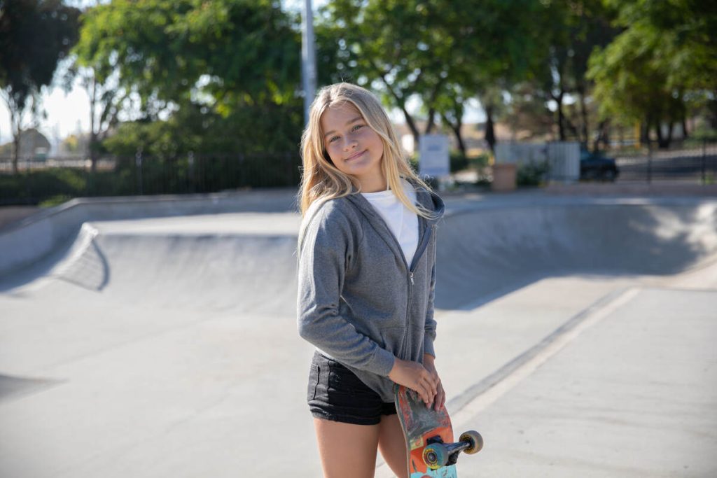 smiling girl with skateboard wearing summer clothes