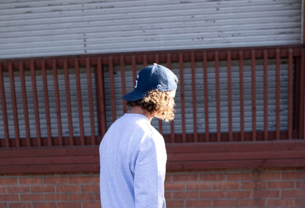 man with curly hair wears blue dad hat