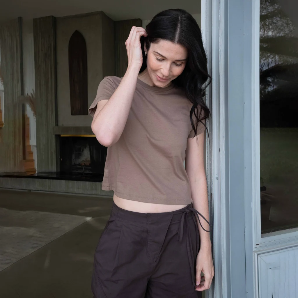 Woman wearing Cotton Heritage OW1086 women's high-waisted tee with dark trousers.