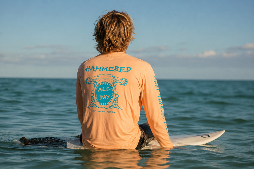 Surfer sitting on a board in a custom Chef Threads Hammered All Day Paragon Islander Long Sleeve sunshirt, printed with Apliiq